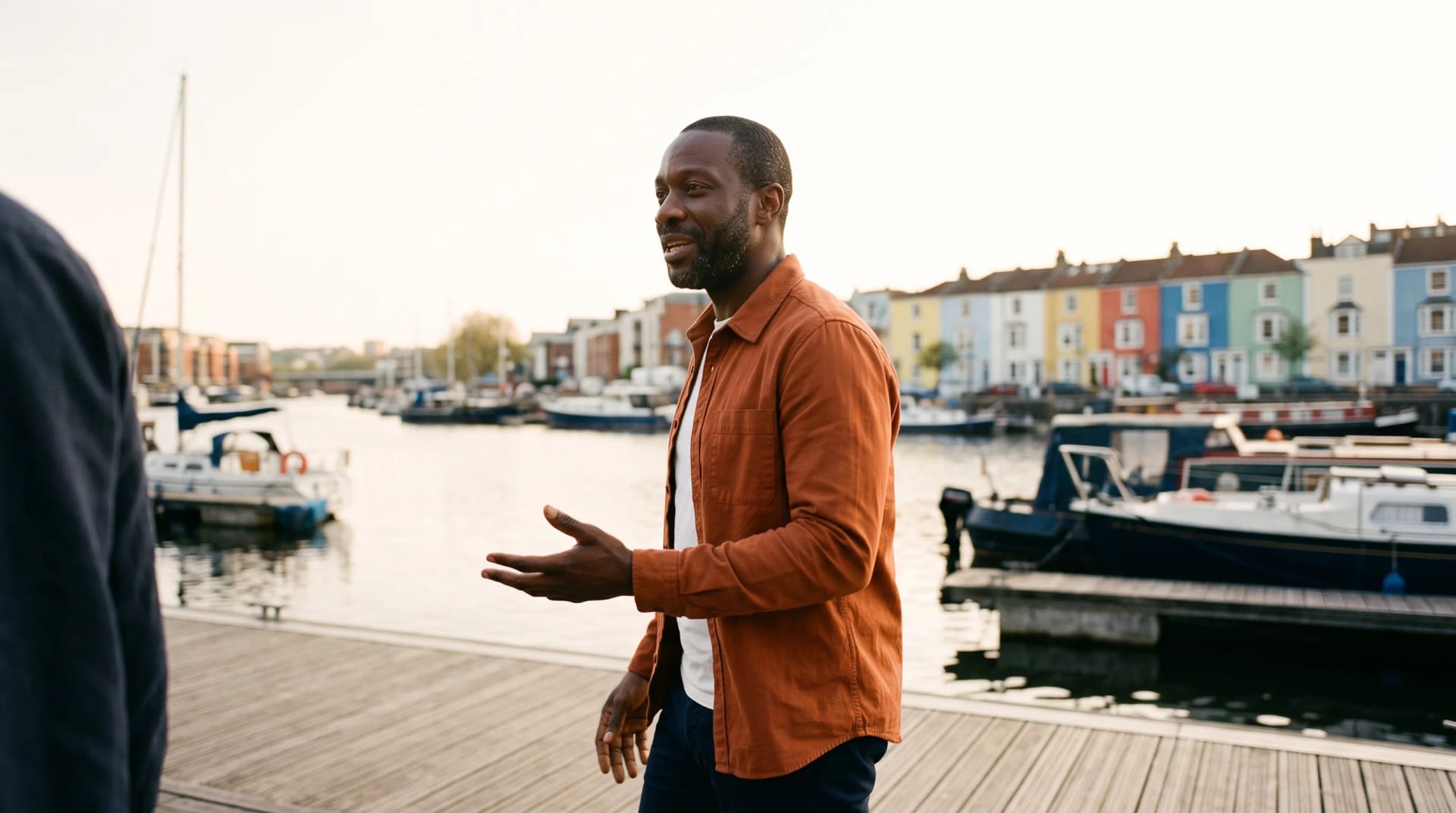 Marcus Grant mid-conversation on a harbourside walk in Bristol, companion out of frame